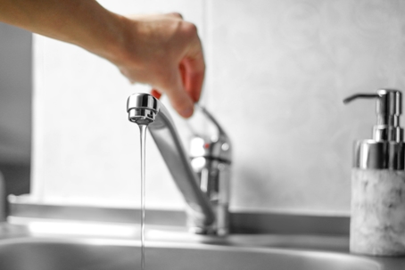 Hand opens the water tap.
