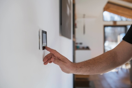 man adjusting smart thermostat